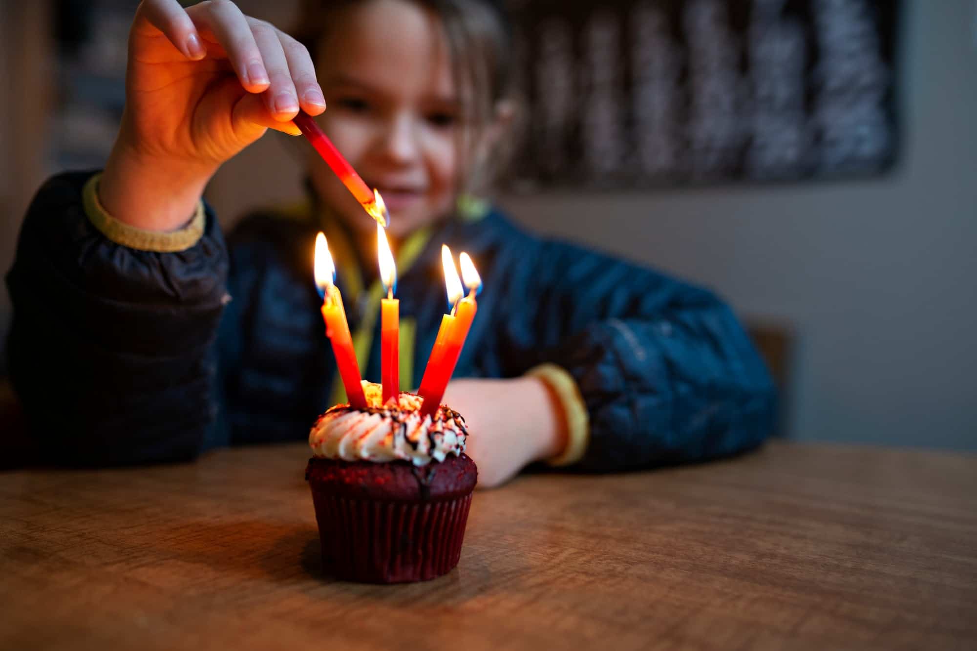 little girl lighting birthday candles on a birthday cake
