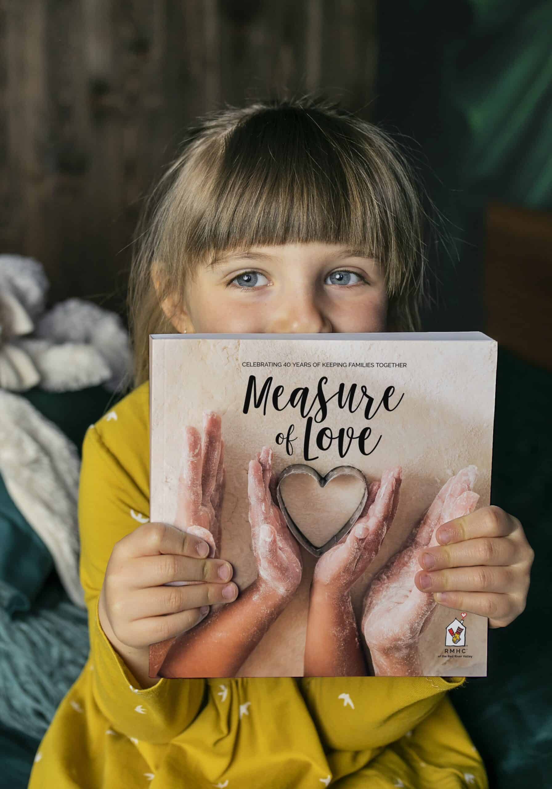 a young girl holding the Measure of Love Cookbook