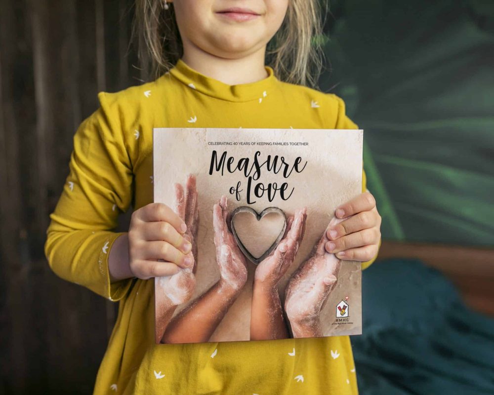 standing smiling girl holding the Measure of Love Cookbook
